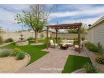 Backyard area with a pergola, comfortable seating, fire pit, water fountain feature, and lush landscaping at 419 National St, Henderson, NV 89015