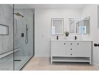 Modern bathroom featuring a double sink vanity and glass enclosed shower with marble tile at 5516 Ness Ave, Las Vegas, NV 89118