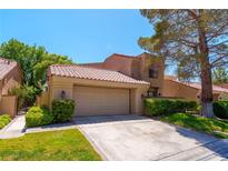 Charming home featuring a red tile roof, a two-car garage, and lush green landscaping at 7625 Spanish Bay Dr, Las Vegas, NV 89113