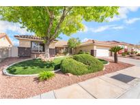 Landscaped front yard featuring green grass, mature tree, and rock garden at 3436 Camsore Point Ln, Las Vegas, NV 89129