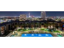 Night view of a luxury condominium rooftop pool and lounge area, with the city skyline in the background at 353 E Bonneville Ave # 1302, Las Vegas, NV 89101