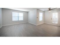 Bright living room featuring wood-look flooring, two windows, a ceiling fan, and a glass door at 5055 W Hacienda Ave # 2125, Las Vegas, NV 89118