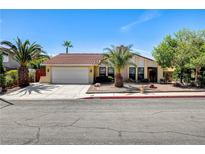 Charming single-story home with a lush front yard, palm trees, and a two-car garage at 8705 Orvieto Dr, Las Vegas, NV 89117