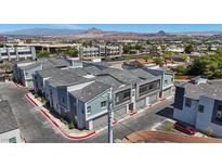 View of modern townhouses featuring gray siding, private garages, and street parking at 143 Aqua Commons Ln, Henderson, NV 89015
