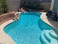 Inviting pool with a rock waterfall feature, perfect for relaxation and outdoor enjoyment at 2078 Wildwood Lake St, Henderson, NV 89052