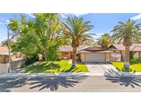 Charming single-story home featuring a well-manicured lawn, mature trees, and a two-car garage at 2426 La Pluma St, Henderson, NV 89014