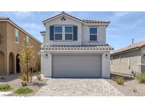 Charming two-story home featuring a gray two-car garage, brick driveway, and well-manicured landscaping at 10273 Fragrant Apple Ct, Las Vegas, NV 89141