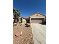 Inviting single-story home with a two-car garage, desert landscaping, and a mature palm tree at 2562 Downeyville Ave, Henderson, NV 89052