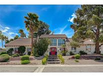 Stunning two-story home featuring a tile roof, landscaped yard, and a striking red double-door entryway at 3151 Coachlight Cir, Las Vegas, NV 89117