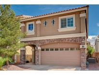 Charming two-story home featuring a two-car garage with a stone archway and manicured landscaping at 5239 Tartan Hill Ave, Las Vegas, NV 89141