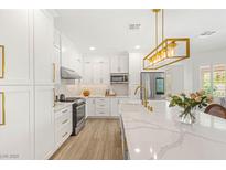 Bright kitchen with stainless steel appliances, white cabinetry, and large center island with marble countertops at 9615 Sedona Hills Ct, Las Vegas, NV 89147
