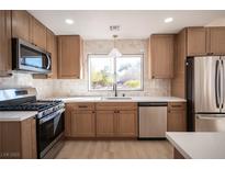 Beautiful kitchen featuring stainless steel appliances, wood cabinets and a large window with a view of the backyard at 9817 Kernville Dr, Las Vegas, NV 89134
