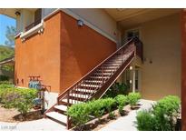 Condo exterior with tan paint, stairs to the front door, and green shrubbery at 1000 Duckhorn Ct # 102, Las Vegas, NV 89144