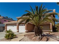 Charming home with a three-car garage and well-maintained landscaping and desert landscaping with a palm tree in the yard at 1066 Aspen Valley Ave, Las Vegas, NV 89123