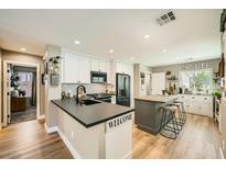 Charming kitchen featuring modern appliances, white cabinets, a kitchen island with seating, and sleek black countertops at 3257 River Glorious Ln, Las Vegas, NV 89135