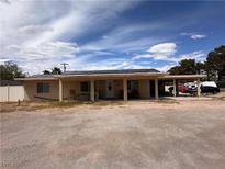 Single story home featuring a covered entryway, carport, and solar panels on the roof at 330 E Shelbourne Ave, Las Vegas, NV 89123