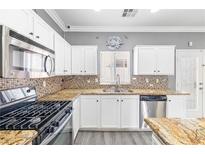 Well-lit kitchen featuring white cabinets, granite countertops, stainless steel appliances, and a mosaic backsplash at 3532 Carisbrook Dr, North Las Vegas, NV 89081