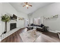 Inviting living room with a painted brick fireplace, wood floors, and vaulted ceiling at 504 Crony Ave, Henderson, NV 89011