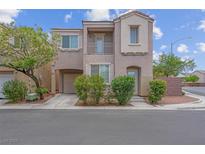 Two-story tan home featuring an attached garage, balcony and landscaped front yard at 6599 Netherseal Ave, Las Vegas, NV 89139