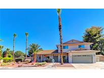 Charming two-story home with a well-manicured yard and mature palm trees under a bright blue sky at 893 Fairway Dr, Boulder City, NV 89005