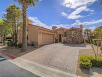 Charming home with a well-kept brick driveway, lush landscaping, and beautiful stone accents at 15 Avenza Dr, Henderson, NV 89011