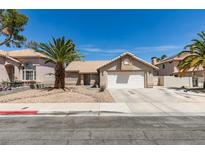Charming single-story home featuring a two-car garage, desert landscaping and mature palm trees at 1824 Dawn Ridge Ave, Henderson, NV 89074