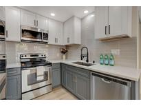 Updated kitchen with stainless steel appliances, white quartz countertops, and modern gray backsplash at 5020 Village Dr, Las Vegas, NV 89142