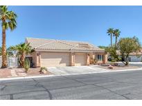 Charming single-story home featuring a three-car garage and desert landscaping with palm trees under a clear blue sky at 5808 Spinnaker Reach Ave, Las Vegas, NV 89130
