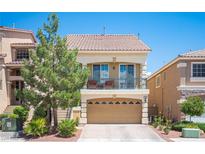 Charming two-story home with a balcony, two-car garage, and desert landscaping under a clear blue sky at 9450 Niagara Landing St, Las Vegas, NV 89139
