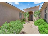 Welcoming front entrance featuring lush landscaping, a covered entryway, and a decorative front door at 10372 Premia Pl, Las Vegas, NV 89135