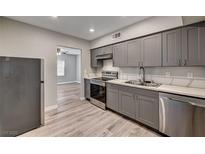 Modern kitchen featuring gray cabinets, stainless steel appliances, and wood-look flooring at 155 Magnesium St, Henderson, NV 89015