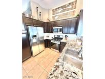 Well-lit kitchen featuring stainless steel appliances, granite countertops, and stylish dark cabinetry at 3329 Hidden Ridge St, Las Vegas, NV 89129