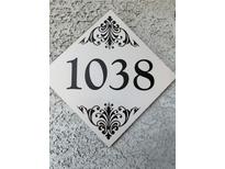 Close up of the house number 1038 on a decorative plaque mounted to a textured wall at 6955 N Durango Dr # 1038, Las Vegas, NV 89149