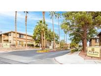 Condominium complex featuring lush landscaping and well-maintained buildings with palm trees against a clear blue sky at 7300 Pirates Cove Rd # 2045, Las Vegas, NV 89145