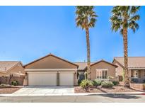 Charming single-story home with a three-car garage, desert landscaping, and two palm trees at 7473 Crystal Clear Ave, Las Vegas, NV 89113