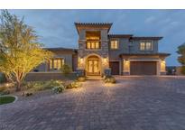Beautiful two-story home featuring manicured landscaping, a spacious three-car garage, and a welcoming brick driveway at 2 Olympia Outlook Dr, Las Vegas, NV 89141