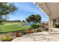 Stunning backyard view of a golf course and pond, framed by a covered patio and water feature at 2864 Sumter Valley Cir, Henderson, NV 89052