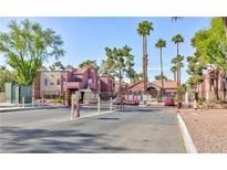 Gated community entrance featuring brick buildings, mature landscaping, and ample parking at 4050 Pacific Harbors Dr # 107, Las Vegas, NV 89121