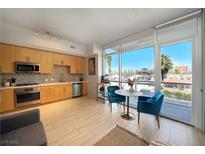 Modern kitchen featuring stainless appliances, natural wood cabinetry, and dining area with large windows at 353 E Bonneville Ave # 215, Las Vegas, NV 89101