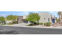 Modern home with minimalist design, xeriscaping, and spacious driveway leading to a black glass-paneled garage door at 668 Falcon Summit Ct, Henderson, NV 89012