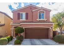 Two-story stucco home featuring a two-car garage, manicured landscaping, and a charming, covered front entry at 7769 Peaceful Trellis Dr, Las Vegas, NV 89179
