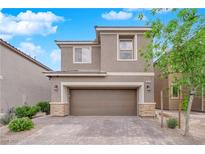 Two-story home featuring neutral stucco, stone accents, a two-car garage, and a paved driveway at 10029 Cluny Ave, Las Vegas, NV 89178