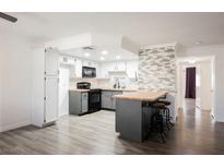 Bright kitchen with wood floors, white cabinets, island with seating and accent tile at 1316 Driscoll Dr # 201, Las Vegas, NV 89128