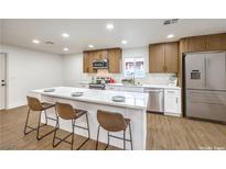 Modern kitchen featuring an island with seating, stainless steel appliances, and wooden cabinets at 2536 Herrod Dr, North Las Vegas, NV 89030