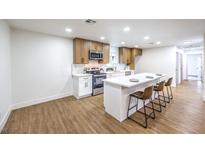 Modern kitchen features stainless steel appliances, white cabinets, quartz countertops, and an island with bar seating at 2536 Herrod Dr, North Las Vegas, NV 89030