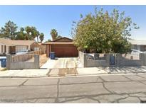 Single-story home with a spacious driveway and a well-maintained concrete and iron fence and a mature shade tree at 408 Rhoda St, Las Vegas, NV 89110