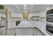 Bright kitchen with white cabinets, stone countertops, stainless steel appliances, and an island at 7217 Mission Hills Dr, Las Vegas, NV 89113