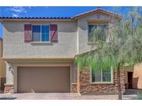Charming two-story home with a two-car garage, stone accents, and colorful, desert landscaping at 1114 Junipine Ave, North Las Vegas, NV 89081