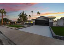 Charming single-story home featuring a putting green and modern garage door at dusk at 2909 Gilmary Ave, Las Vegas, NV 89102