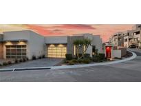 Contemporary home featuring two garage doors, desert landscaping, and a distinctive red front door at 383 Solitude Peak Ln, Henderson, NV 89012